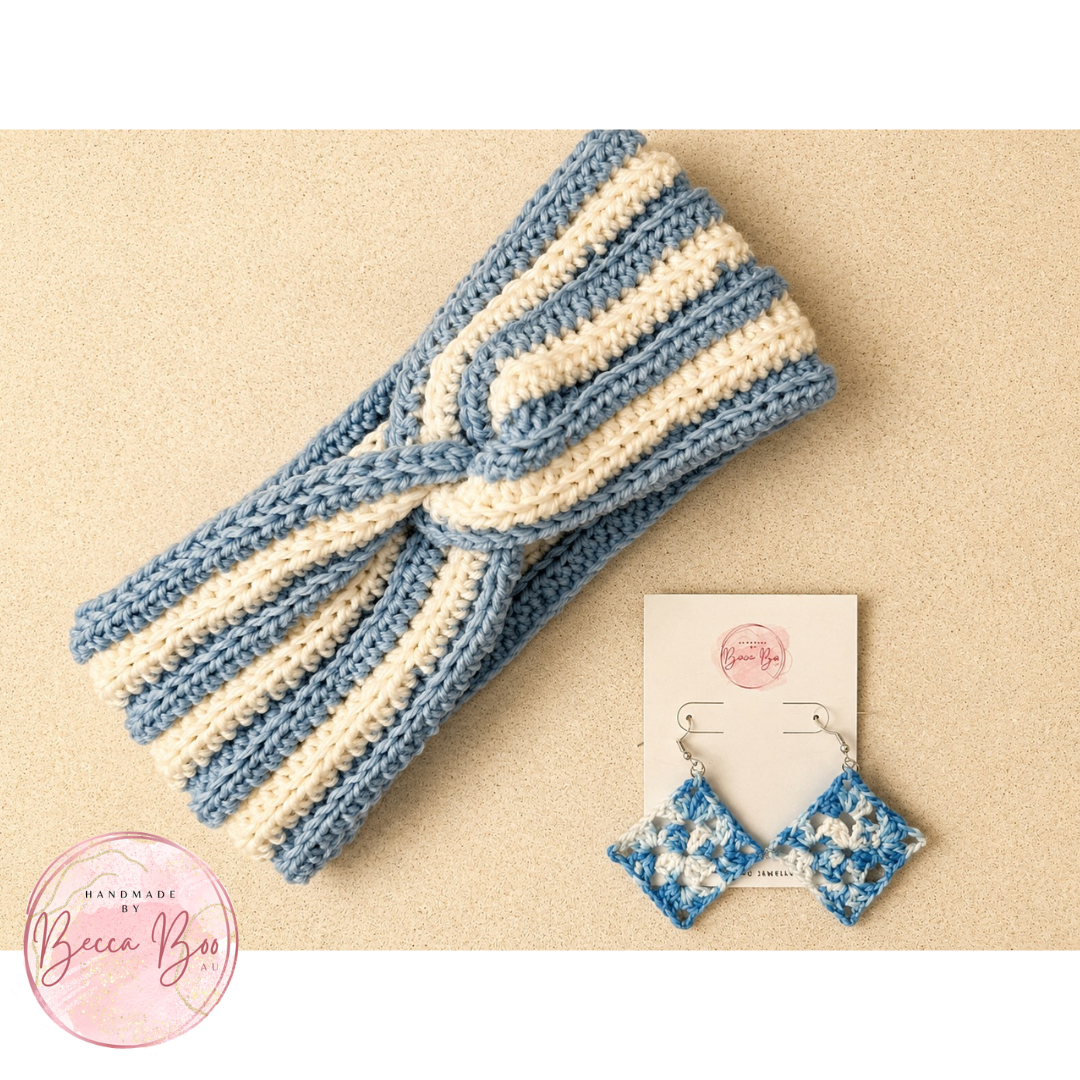 A handmade crocheted ear warmer headband with twisted stripes in pale blue and off-white, displayed next to a pair of matching blue and white patterned earrings on a display card, set against a textured beige background.
