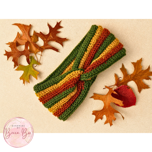 Crocheted ear warmer headband with autumnal colours surrounded by fall leaves on a light background