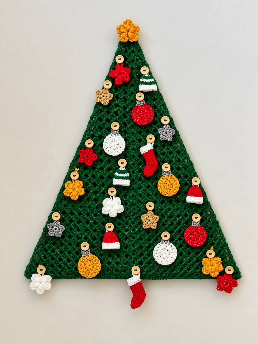 Image of a triangular crocheted green Christmas tree adorned with traditional Christmas coloured crocheted ornaments