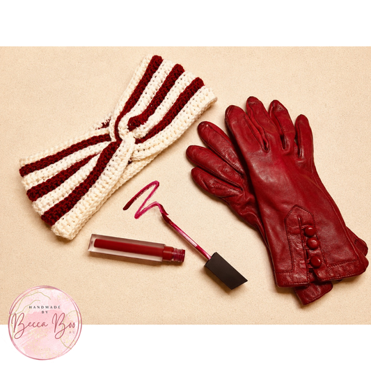 A flat-lay of coordinated winter accessories on a light beige background: a cream and burgundy striped crocheted ear warmer headband, a pair of burgundy leather gloves, a matching burgundy lip gloss tube with the applicator, and a small circular 'Handmade by Becca Boo' logo in the lower left corner.